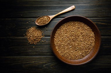 Pişirmeden önce bir tabak dolusu karabuğday ve klasik karanlık bir masada bir kaşık. Restoran ya da otel için tarif ya da menü alanı.