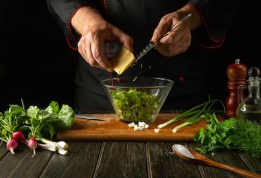 Şef mutfaktaki bir kasede taze sebze salatası hazırlıyor. Taze sebzeli ve sütlü peynirli lezzetli salata..