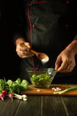 Aşçı sebze salatasına tuz ekler. Mutfaktaki şefin elinden vejetaryen yemeği. Otel ya da restoran için menü vejetaryeni fikri.