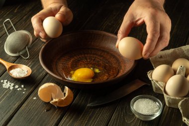 Lokantanın mutfağındaki şefin eliyle nefis bir yumurta. Aşçı pişirmeden önce çiğ yumurta tutar. Yumurta diyeti..