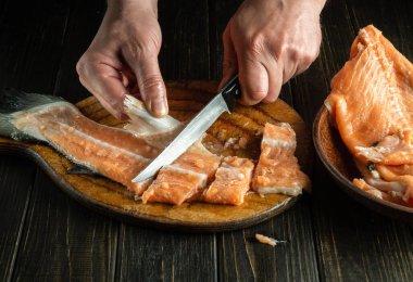 Şef bir balık yemeği hazırlamadan önce bir bıçakla taze balığı kesme tahtasıyla keser. Mutfak masasında balık diyeti..