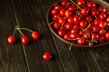 Koyu bir masada eski bir tabakta kirazlar. Tatlı olarak vişne. Diyet için tatlı meyveler..