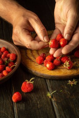 Şef mutfaktaki kavanozda çileklerden bir içecek hazırlıyor. Dereotuyla doldurup şeker eklemeden önce fragaria üzümlerini temizleyip sınıflandırmak.