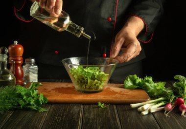 Deneyimli şef sebze salatasına zeytinyağı ekler. Lokanta mutfağında aşçı elleriyle vejetaryen yemeği. Otel için vegan menüsü fikri