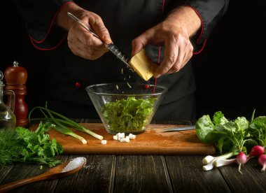 Deneyimli aşçı mutfakta bir kasede taze sebze salatası hazırlar. Taze sebzeli ve sütlü peynirli lezzetli salata. Sebzelere peynir ekliyorum.