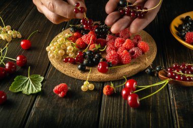 Olgun böğürtlenlerden meyve suyu hazırlama. Aşçı, vitamin tatlısı hazırlamadan önce mutfak masasında ahududu ve frenk üzümü ayırır. Reklam için alan