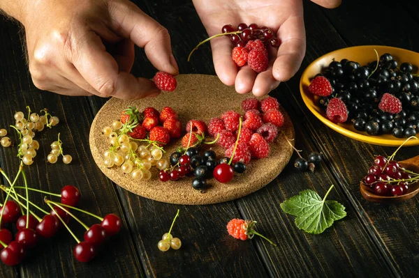 Close-up of the cook hands with raspberries. Sorting and selecting berries in the kitchen to prepare a fruit drink or juice