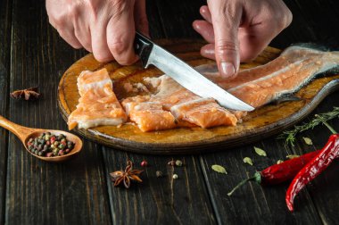 Mutfak tahtasına çiğ somon balığı kesen bir şefin elleri. Restoran ya da otel için lezzetli kırmızı balık yemeği..