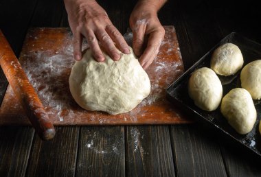 Fırıncının elleri yakın plandaki çörekler için hamur hazırlıyor. Fırıncı sosisli börek pişirir..