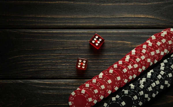 Poker dice or dice game on a black wooden table and chips from a lucky win. Free dark space for ads. Luck in gambling.