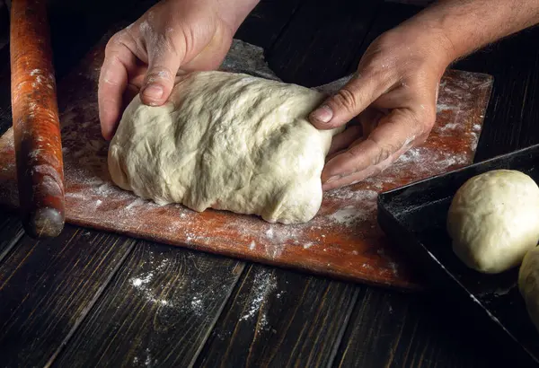 Hamuru pişirmek için hamur hazırlayan fırıncı elleri yakın plan. Fırında sosisli sandviç pişirme fikri..