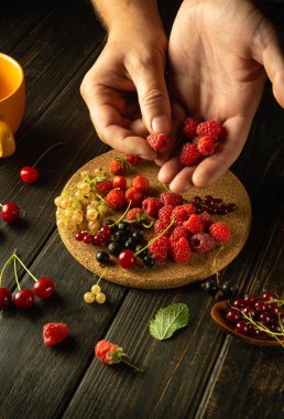 Mutfak masasında bir sürü taze meyve var. Meyve suyu ya da komposto hazırlamadan önce insanın elleri ahududu ayırıyor..
