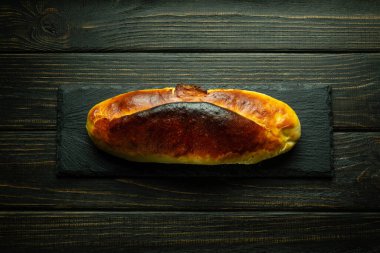 Siyah ayıklama tahtasının üzerinde ev yapımı turta. Koyu arkaplanda aşçılık konsepti.