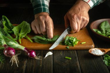 Erkek eller ıspanağı bıçakla kesiyor. Mutfakta bir şefin elleriyle sebze salatası pişirmek. Vejetaryen diyeti fikri