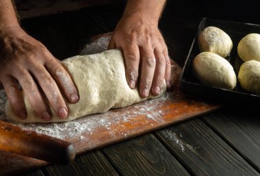 Fırıncı eller hamuru çörekler veya turtalar için yoğurur. Fırında şekerleme pişirme konsepti. Boşluğu kopyala