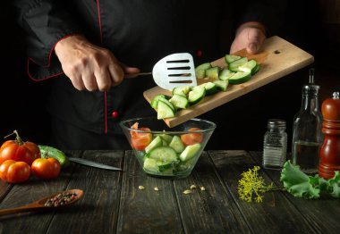 Şef restoranın mutfağında sebze salatası hazırlıyor. Domatesli ve salatalıklı vitamin salatası pişirme kavramı.