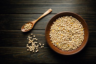 Pişirmeden önce bir tabak kuru bezelye ve bir kaşığın yanına serpiştirilmiş antika bir masa. Siyah arkaplanda tarif veya menü için boşluk.