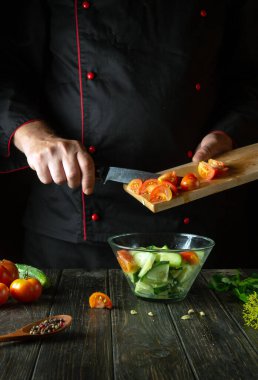 Şef restoranın mutfağında sebze salatası hazırlıyor. Domatesli ve salatalıklı vitamin salatası pişirme kavramı