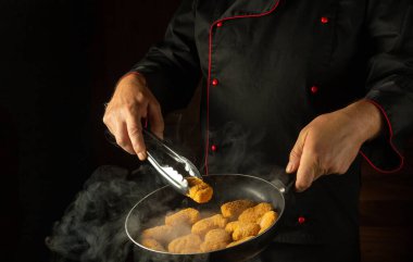 Şef kızartma tavasında çıtır çıtır nagit kızartıyor. Otel ya da restoran için lezzetli kahvaltı kavramı. Siyah arkaplanda tarif veya menü için yer.