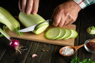 Aşçı kabağı keser. Diyet öğle yemeği için mutfak masasında sebze ve baharatlı ilik pişiriyorum..