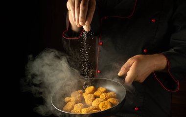 Çıtır tavuk nugget pişiriyorum. Şef sıcak tavaya tuz ekliyor. Reklam alanı olan bir otel için büyük mutfak fikri.