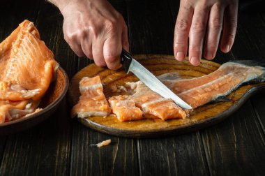 Bir balık tabağı hazırlamadan önce mutfak tahtasındaki taze balıkları keserken ya da temizlerken şefin elleri bıçakla..