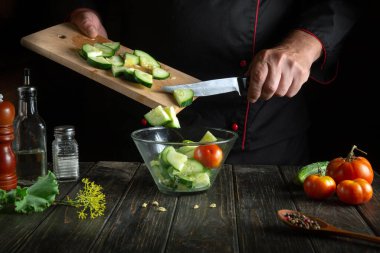 Profesyonel şef mutfakta sebze salatası hazırlıyor. Vitamin Salatasına Taze Salatalık Ekleniyor