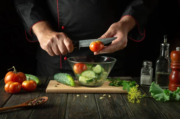 Şef mutfakta sebze salatası hazırlıyor. Bıçakla vitamin salatası için taze domates doğramak..