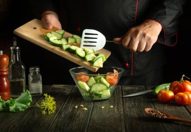 Profesyonel şef, restoranın mutfağında sebze salatası hazırlıyor. Domatesli ve salatalıklı vitamin salatası pişirme kavramı