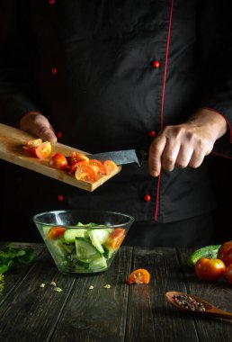 Profesyonel şef, restoranın mutfağında sebze salatası hazırlıyor. Domatesli ve salatalıklı vitamin salatası pişirme kavramı.