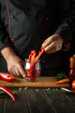 Kavanozda baharatlı biber konservesi. Aşçı bir restoran mutfağında capsicum hazırlar. Kış için sebze hazırlama konsepti