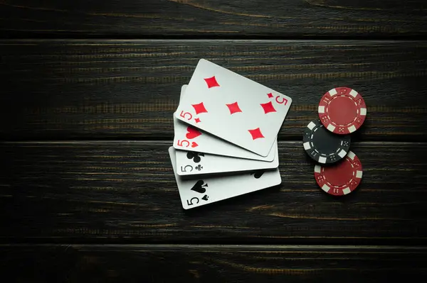 Poker game with four of a kind or quads combination. Chip and cards on the black vintage table in poker club.