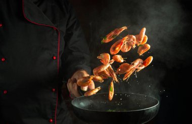 Deneyimli şef sıcak tavada buharlı karides pişirir. Deniz ürünleri pişirme, sağlıklı vejetaryen yemekleri ve siyah arka planda yeme kavramı. Hareketsiz kal. Tarif veya menü için boş alan