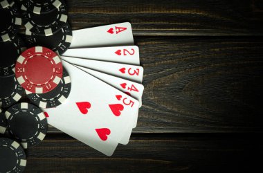 Kazanan yüksek kart kombinasyonuyla poker oynayan popüler ve kumarbaz. Poker kulübündeki siyah bir masada fişleri olan kartlar.