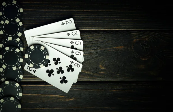 A popular poker game with a winning straight flush combination. Playing cards with chips on a black vintage table in a poker club. Free space for advertising
