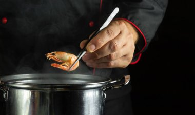 Kaynar tavada karides pişirmek. Lezzetli ve sağlıklı deniz ürünleri. Kaşıkta kaynamış karides ya da şef eli..