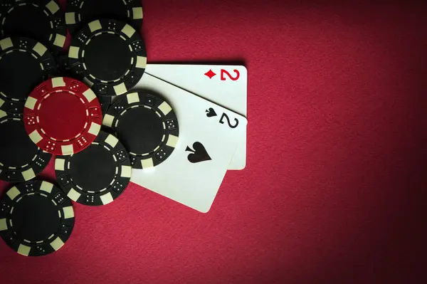 A gambling game of poker with a winning combination of one pair. Cards with chips on a red table in a poker club. Space for advertising.