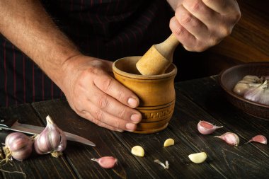 Aşçı yemeğe eklemeden önce mutfak masasındaki sarımsağı hazırlar. Sarımsak doğrarken bir şefin ellerini yakın plan çek. Sağlıklı köylü yemeği konsepti.