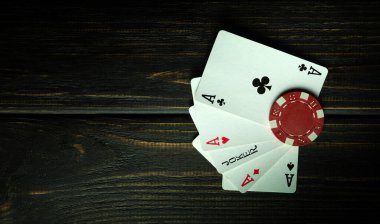 Birbirinin aynı beş kart kombinasyonlu popüler bir poker oyunu. Poker kulübündeki siyah bir masada çip ve aslar..