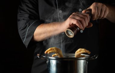 Aşçı kaynar tavuk budu tenceresine kuru biber ekler. Restoranın mutfağında ya da otelinde lezzetli çorba ya da et suyu hazırlama kavramı.
