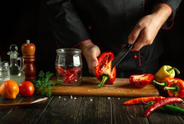 Bir şef bir restoran mutfağında kırmızı biber hazırlar. Kavanozda pişirmeden ya da konserve vermeden önce bıçakla biber soymak.
