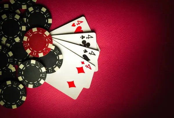 A popular poker game with a winning hand of four of four of a kind or quads. Cards and chips from winning on a red table in a poker club.