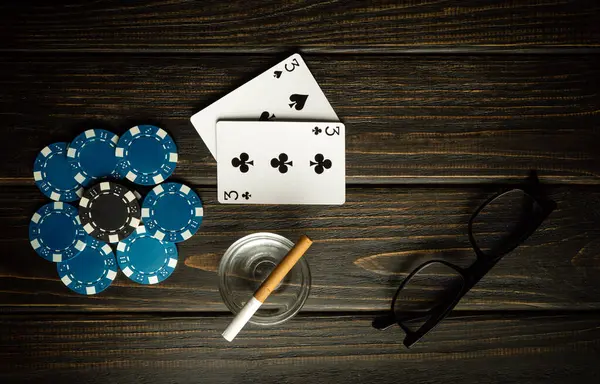 An interesting poker game with a winning combination of one pair. Cards with chips and glasses with a cigarette on a dark vintage table in a poker club.