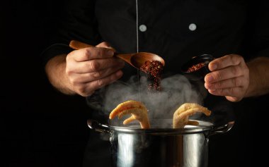 Aşçı kaynayan tavuk budu tenceresine aromatik baharat katar. Restoranın mutfağında ya da otelinde lezzetli çorba ya da et suyu hazırlama kavramı.