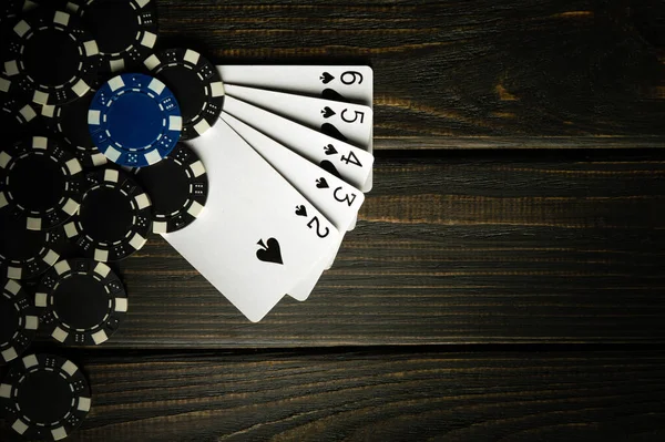 A popular and exciting poker game with a winning straight flush combination. Cards with chips on a dark vintage table in a poker club.