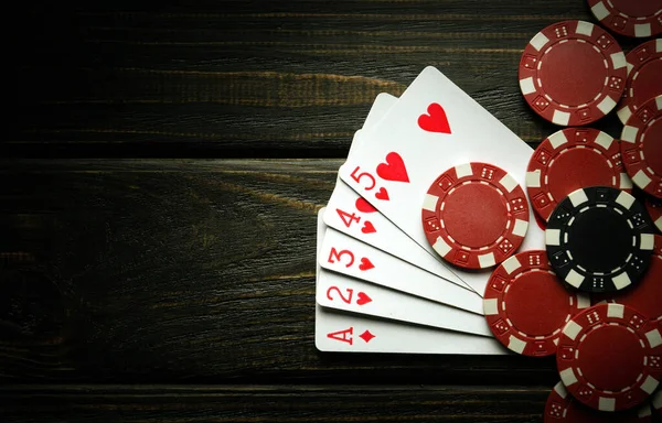 A gambling game of poker with a winning combination of high cards. Cards with chips on a dark vintage table in a poker club