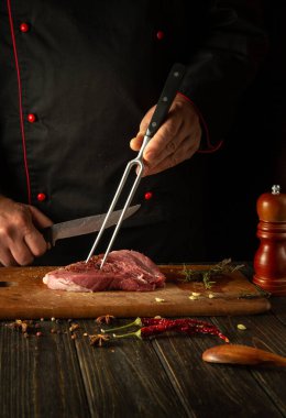 Bifteği bir şefin elleriyle hazırlama süreci. Mutfak masasındaki baharat ve biberiye lezzetli bir et yemeği hazırlamak için..