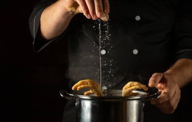 Aşçı bir tencere kaynayan tavuk bacağına tuz ekler. Restoranın mutfağında ya da otelinde lezzetli çorba ya da et suyu hazırlama kavramı.