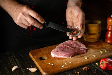 Aroma ve tat için bifteğe kuru baharat ekliyorum. Mutfak masasında bir şefin elleriyle domuz şiş kebap pişirmek..