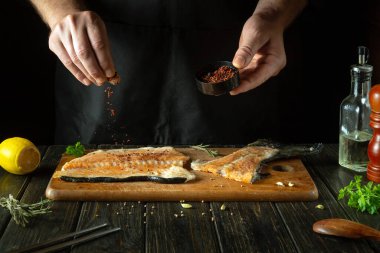 Aşçı otel mutfağında alabalık bifteği tatlandırıyor. Pembe somon, akşam yemeği hazırlamak için lezzetli bir balıktır. Avrupa mutfağı.